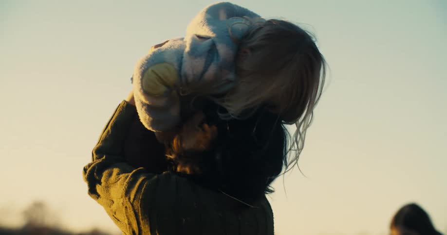 A woman holding a girl in her arms lifting her up then lowering her while hugging and kissing her