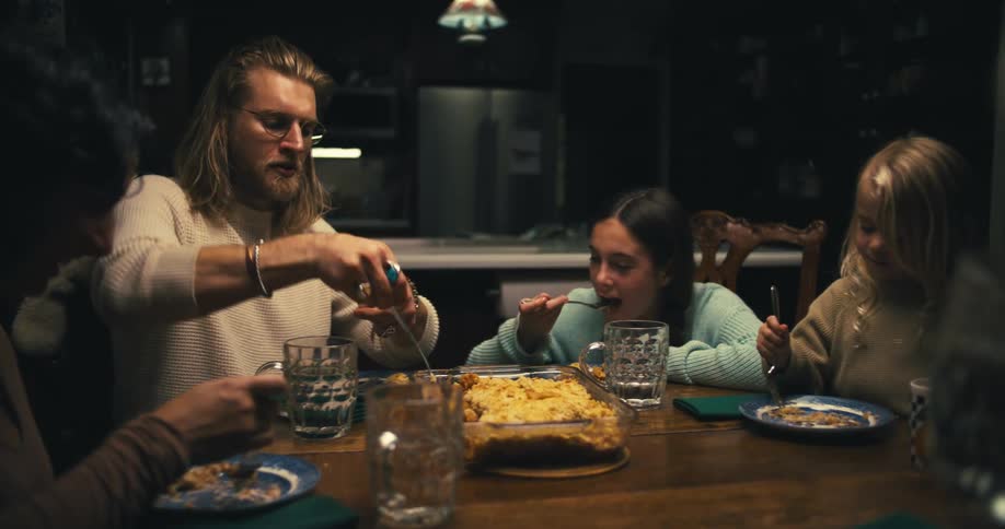 A family has dinner together including two kids a man and two women all eating and talking