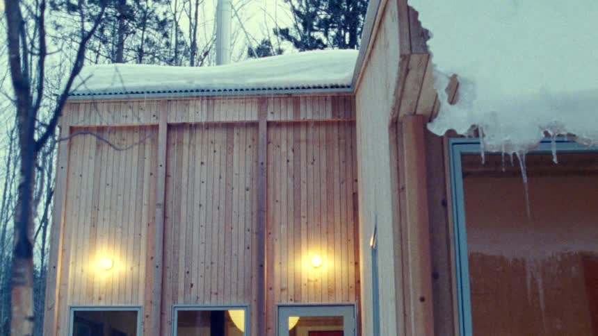 A wooden cabin with snow and lights in a winter forest