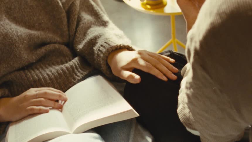 A woman flips the pages of the book while reading