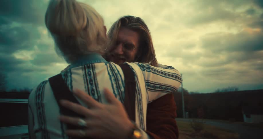Man hugs a child as family gathers at dusk