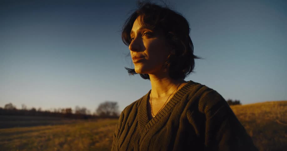 Woman gazes at the horizon illuminated by the golden sunset light