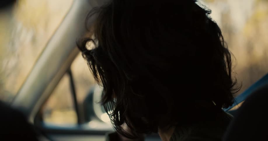 Hand holds the head of a woman inside a car who is crying