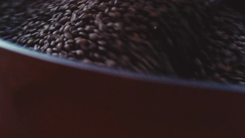 Coffee beans are stirred in a large vat