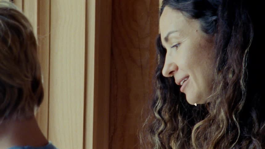 A mother and child are looking out a window and the mother is smiling at the child