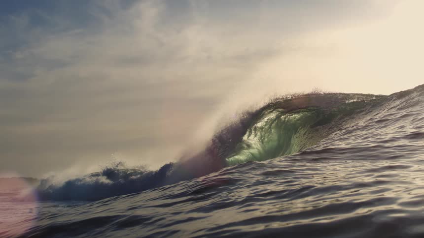 Ocean wave forming with sunlight in the background