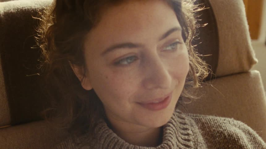 Woman in a brown sweater gazing softly to the side