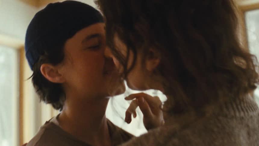A lesbian couple shares a kiss inside a cozy home
