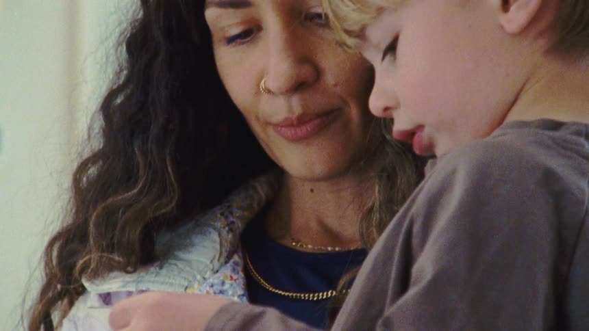Woman closely observes a blond child in a moment of shared focus
