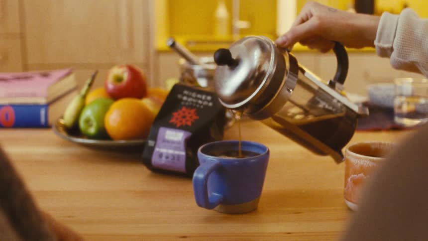 A woman pours coffee into the mug