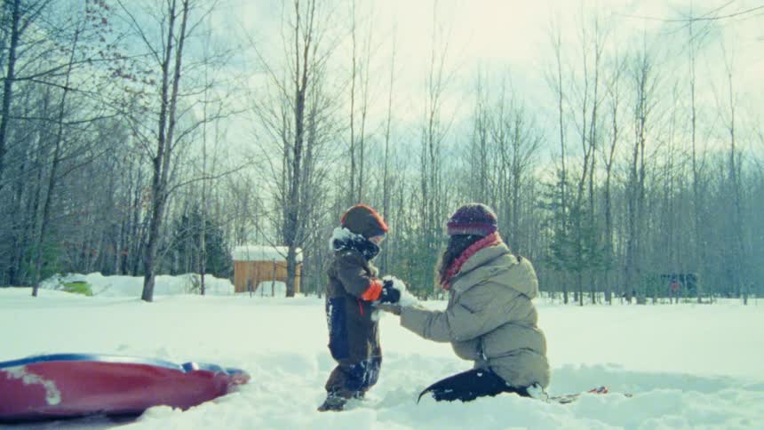 A child throws snow at their mom in a winter forest