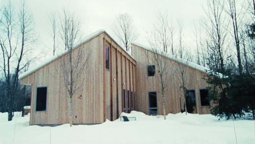 The home is surrounded by trees and snow