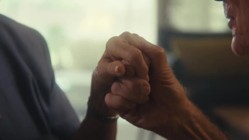 Two elderly hands clasped together in a gesture of unity