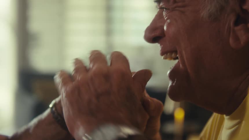 Elderly man laughing as he kisses his female partners hand