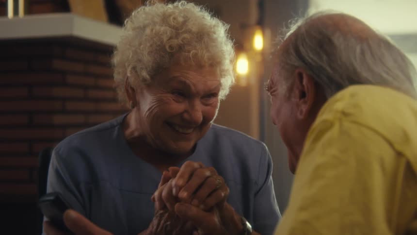 A man and woman get excited and hold hands while looking at a phone