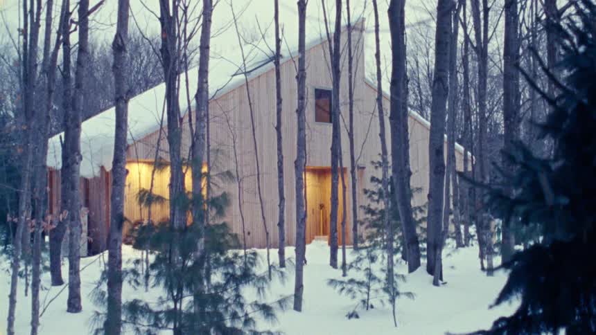 The cabin is surrounded by snow and trees