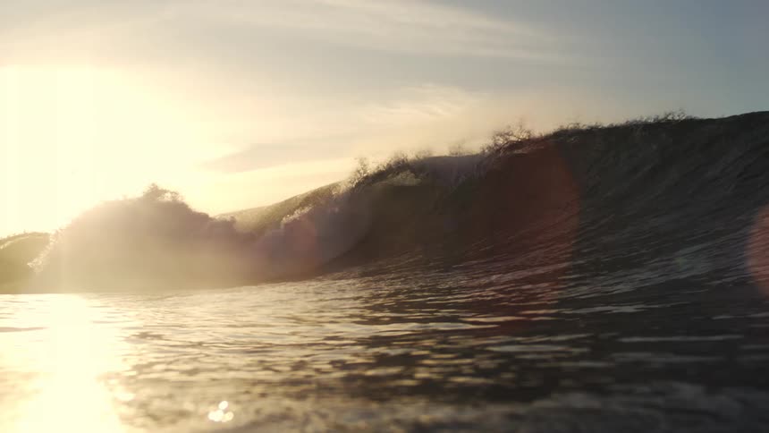 Ocean waves roll at sunset with golden light on the water