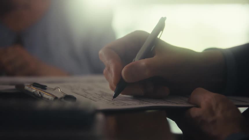 Man filling out a form with a pen