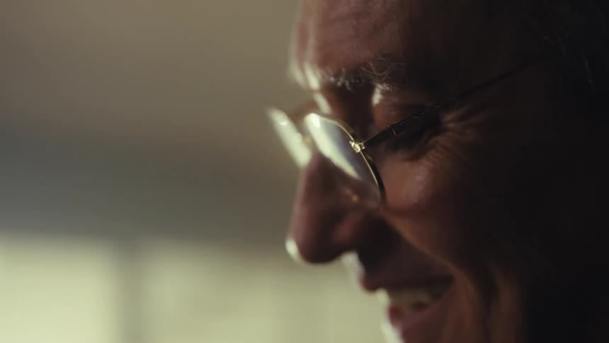 Side closeup of an elderly man with glasses smiling softly