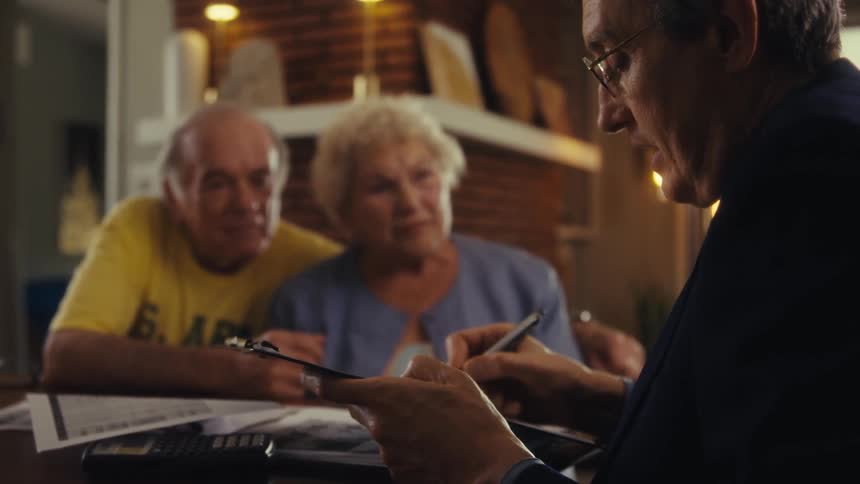 Elderly couple talking with a consultant holding a clipboard and pen