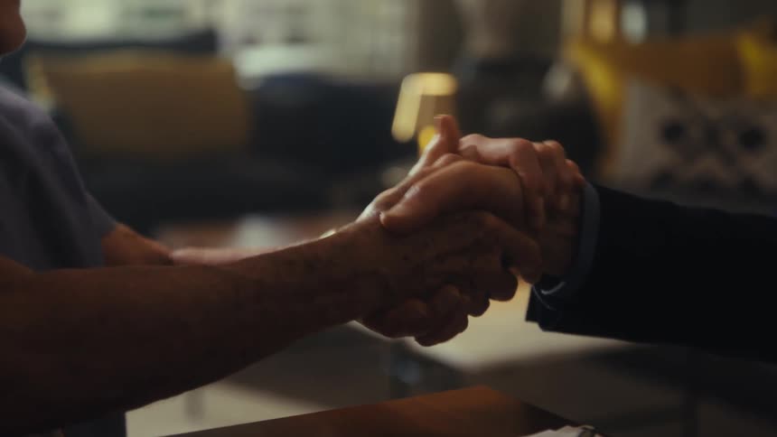 The video shows two men in business suits shaking hands as a sign of agreement or a greeting their hands are clasped tightly together in a professional manner