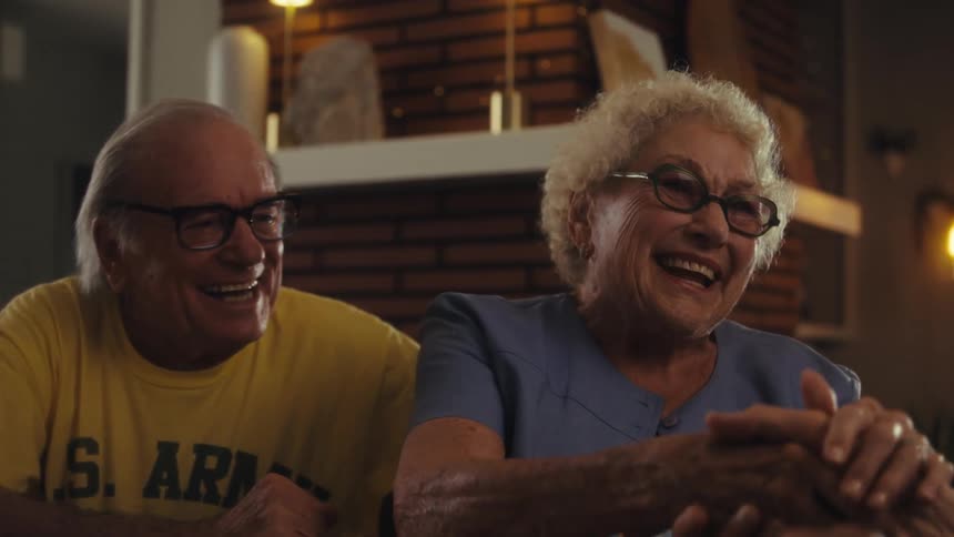 Elderly couple happily shakes hands with a man visiting them at home during the daytime
