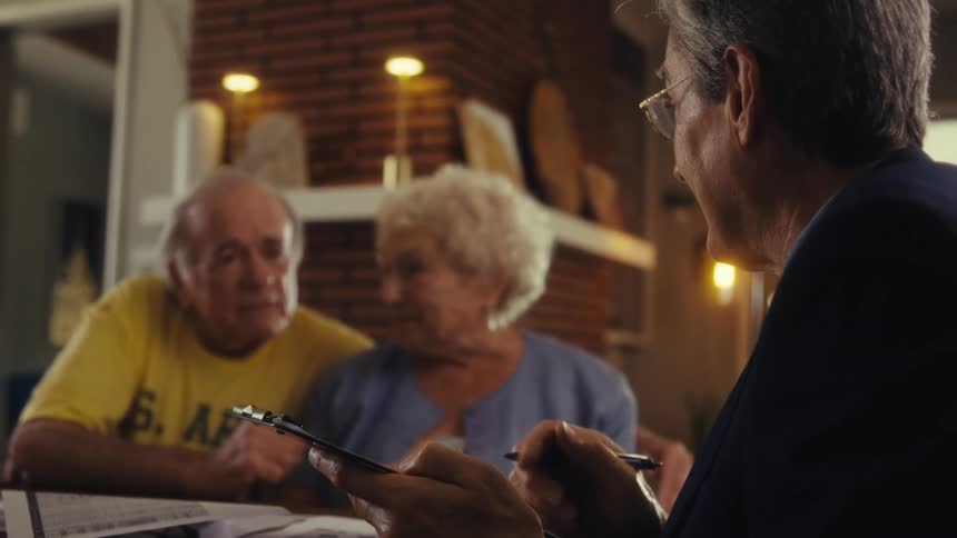 Elderly couple talks with a professional taking notes on a clipboard