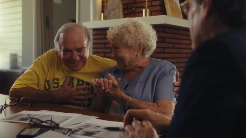 A couple are happy as a man talks with them at home