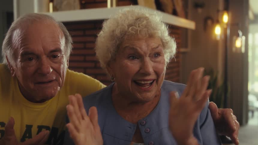 An elderly couple receiving news and celebrating happily