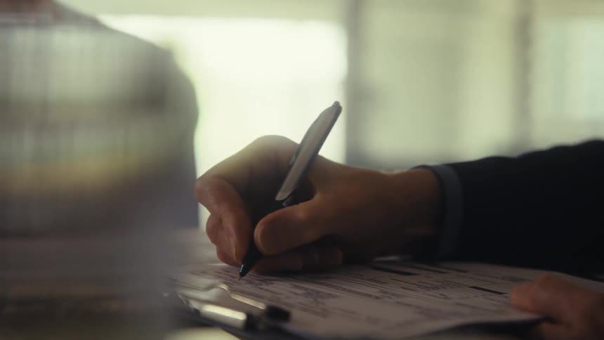 Hand filling out a form with a pen
