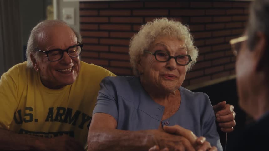 Elderly couple smiles excitedly during a conversation at the table