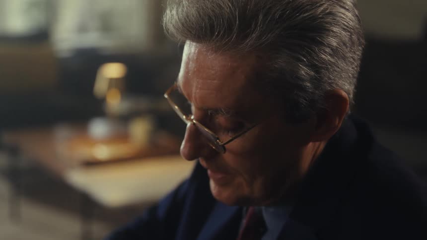 Person in a suit filling out a form clipped to a clipboard