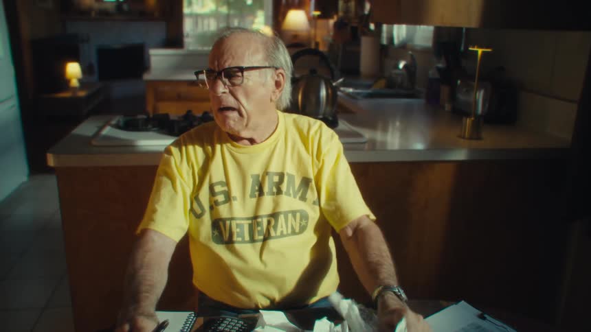 An elderly man looking at multiple bills worried about so many expenses