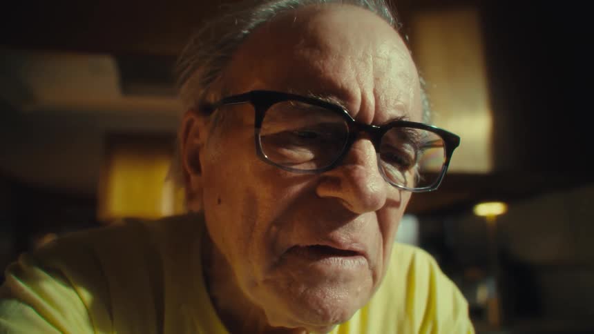 An elderly man reading something on a sheet of paper