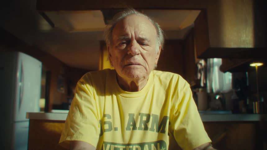 A man sits at a table appearing thoughtful and slightly worried