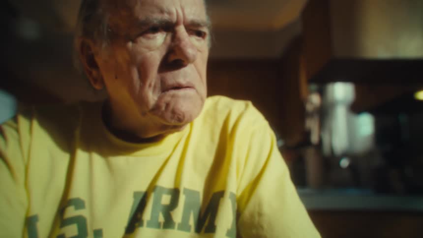 An elderly man with glasses looking at his phone then taking off his glasses with a surprised expression