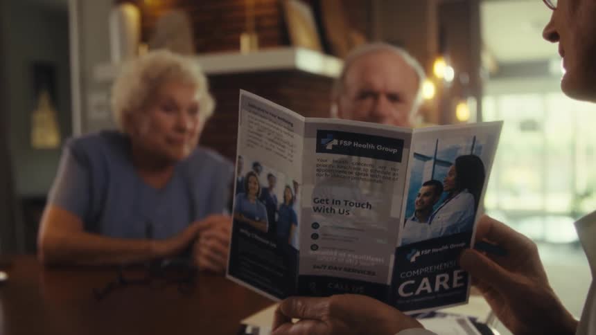 Elderly man showing a health plan brochure to an elderly couple