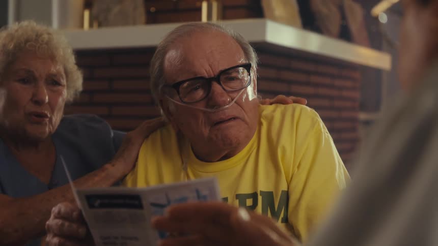 An elderly couple looking sad after receiving news from a woman