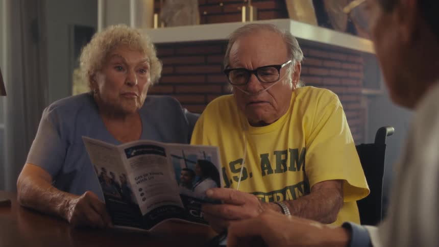 Elderly couple attentively looks at a medical brochure while talking with a healthcare professional