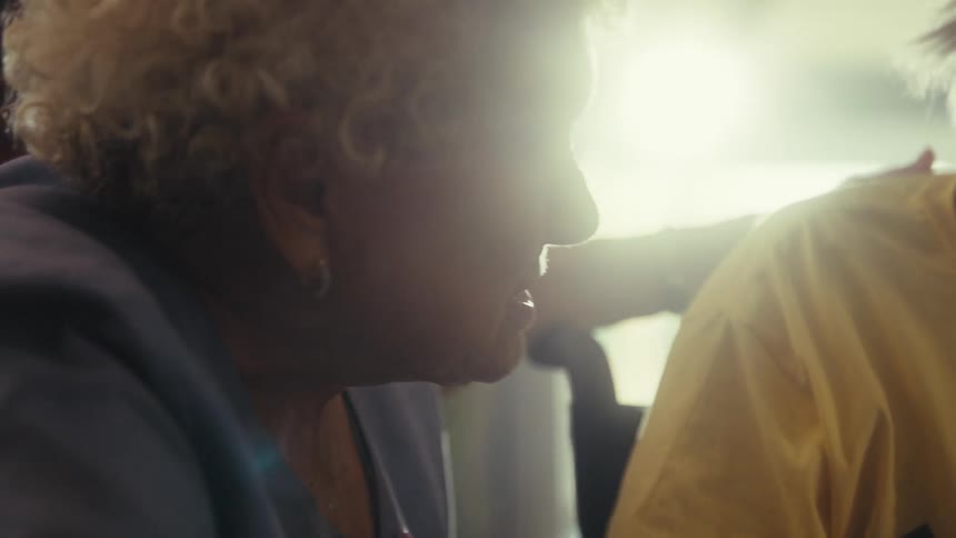 An elderly couple sits side by side having a conversation indoors