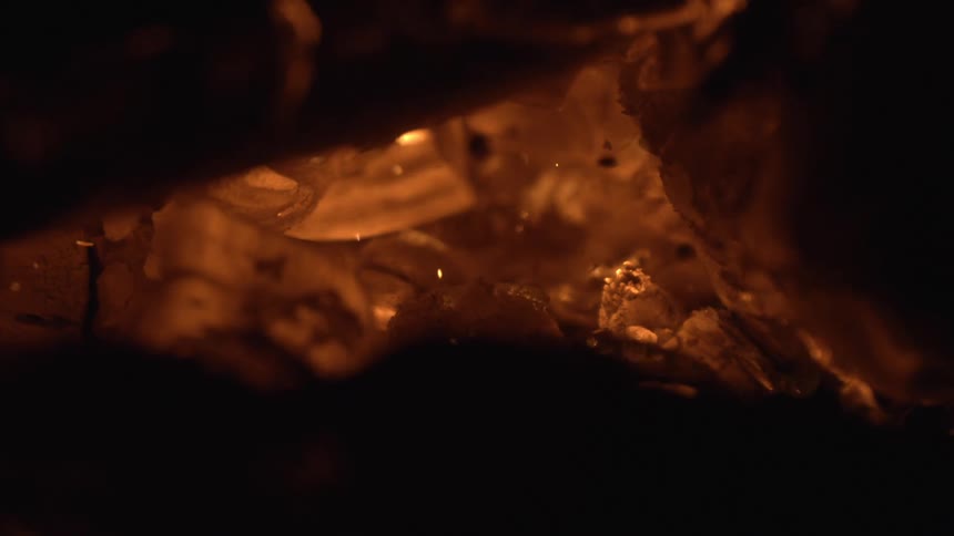 Glowing embers emit a warm orange light among dark charred wood