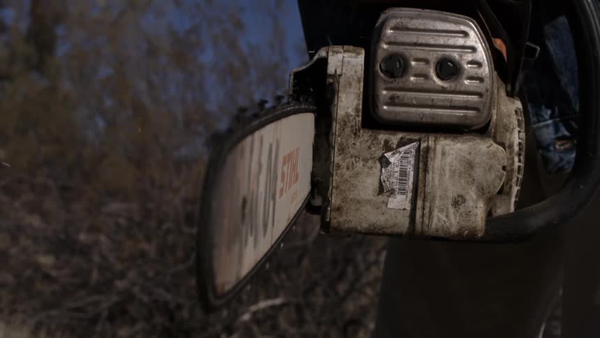 Worn chainsaw being held outdoors