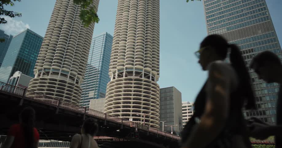 Pedestrians walk in front of circular and modern skyscrapers