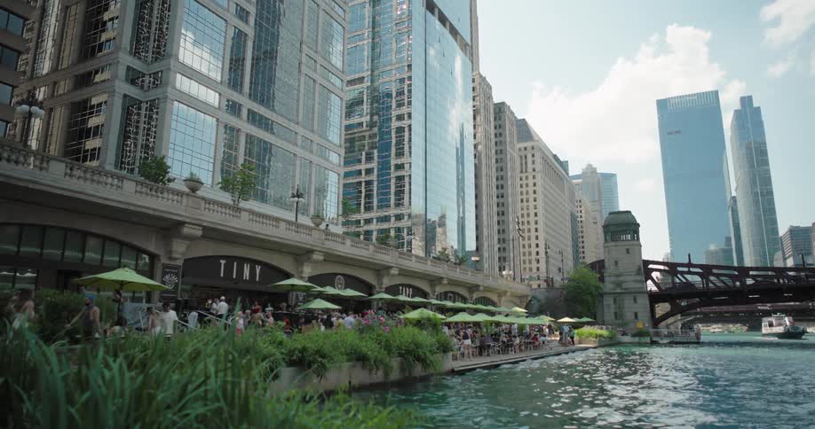 Riverside promenade bustling with cafs and glass buildings in the background