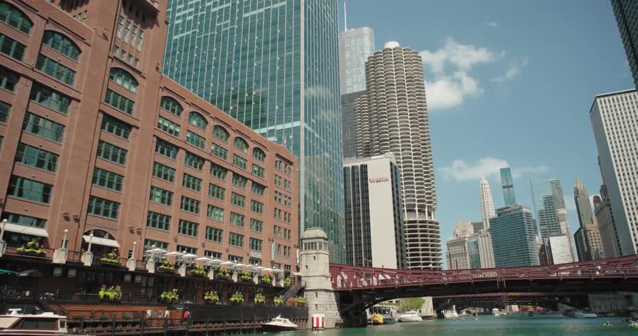Tall buildings along the river with a red bridge in the background