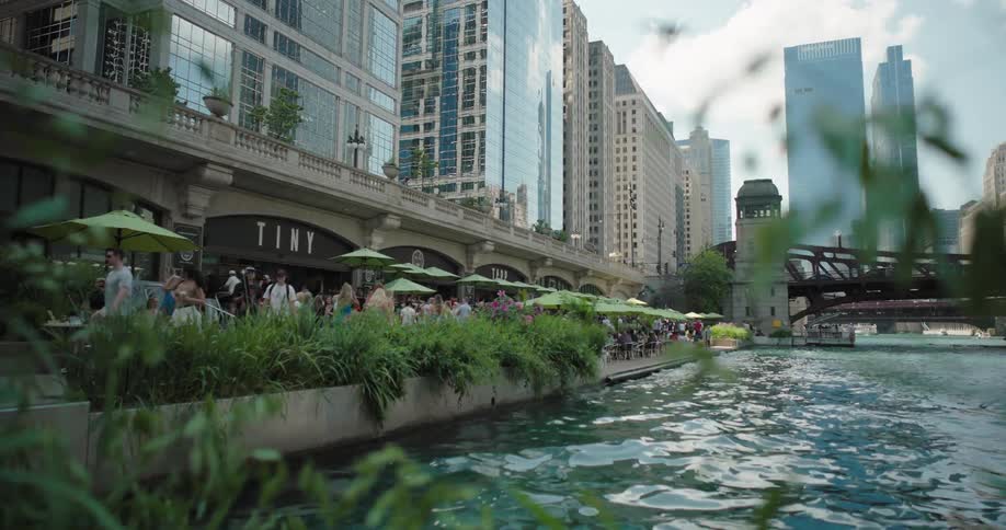 Restaurants and people gathered along a riverside in an urban area