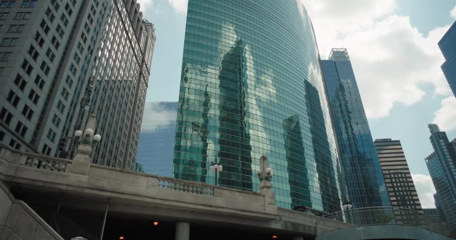 Modern glass skyscrapers rise in the city against a bright sky