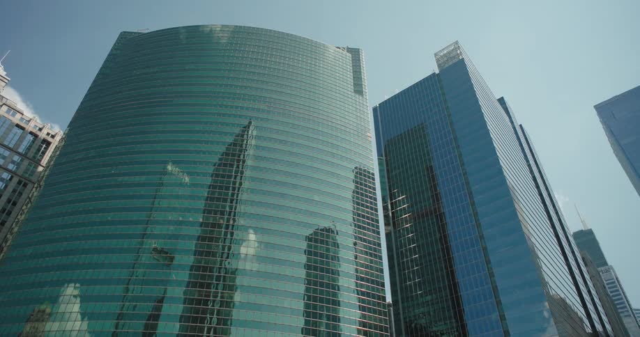 Glass skyscrapers reflect the blue sky and neighboring buildings