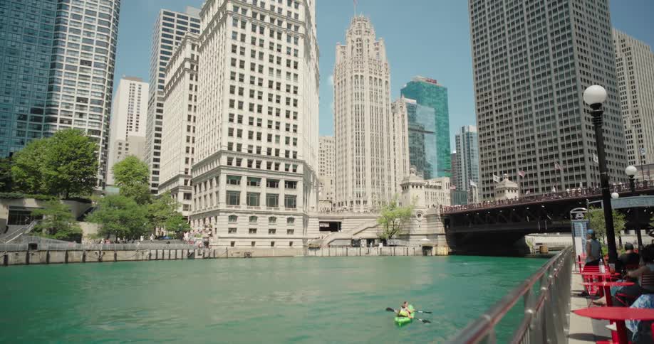Maritime canal in a metropolis with modern skyscrapers and people in restaurants and kayaking