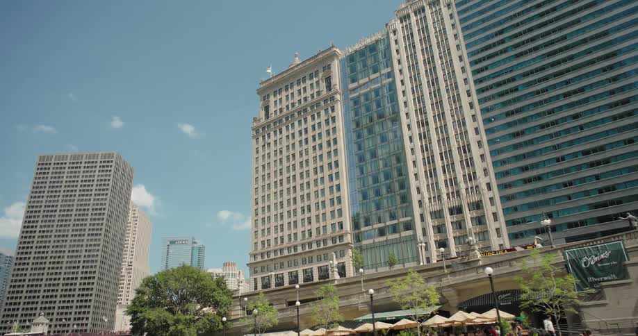 Urban view with tall buildings along a river under the shadow of a bridge